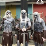Varios modelos caracterizados como White Walkers de Game of Thrones mediante bodypainting de tonos azulados y grisáceos posan juntos. Sus cuerpos están cubiertos con elaborados diseños que imitan piel helada, venas marcadas y rasgos fantásticos, recreando la apariencia de los caminantes blancos de la serie. El grupo se encuentra en una puesta en escena de estilo invernal, con expresiones serias y una atmósfera fría y sobrenatural